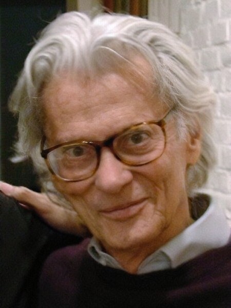 Richard Avedon 晚年的照片，白髮、戴玳瑁色眼鏡，在工作室裡微笑